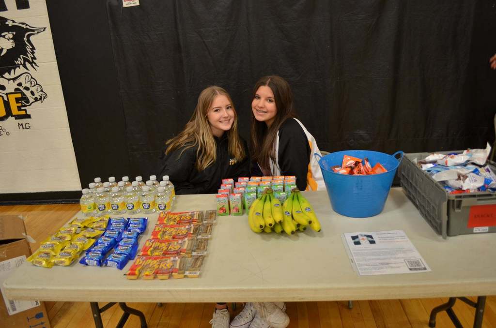 2 girls sitting at a table with snacks and water for blood drive donators